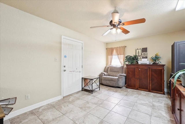 living area featuring light tile patterned floors, a textured ceiling, and ceiling fan