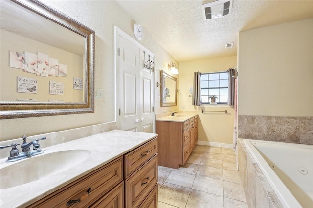 bathroom featuring tile patterned floors, vanity, tiled bath, and a textured ceiling