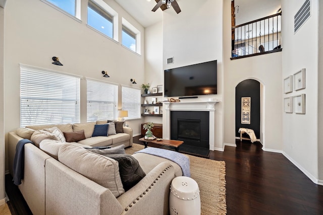 living room with a tiled fireplace, ceiling fan, and dark hardwood / wood-style flooring