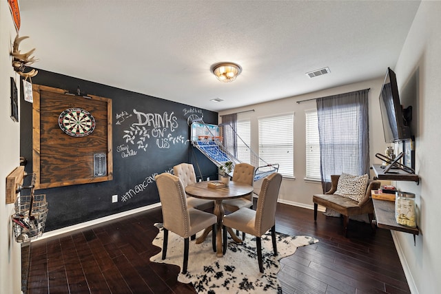 dining space with wood-type flooring and a textured ceiling