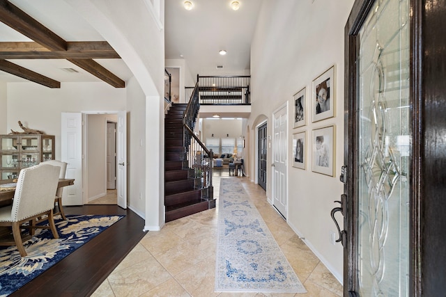 tiled entrance foyer with beamed ceiling and a towering ceiling