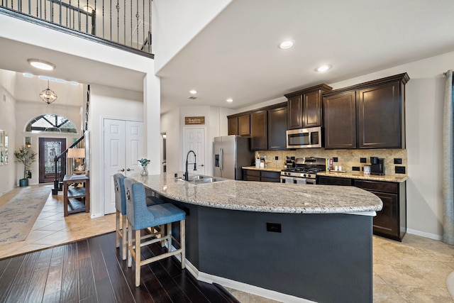 kitchen featuring an island with sink, appliances with stainless steel finishes, sink, and decorative backsplash