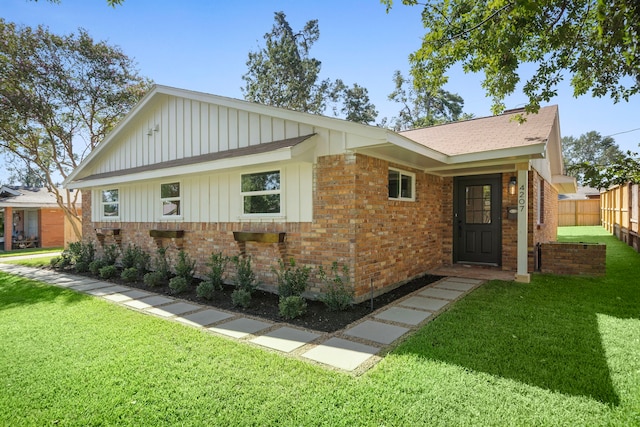 ranch-style house with brick siding, board and batten siding, a front lawn, and fence