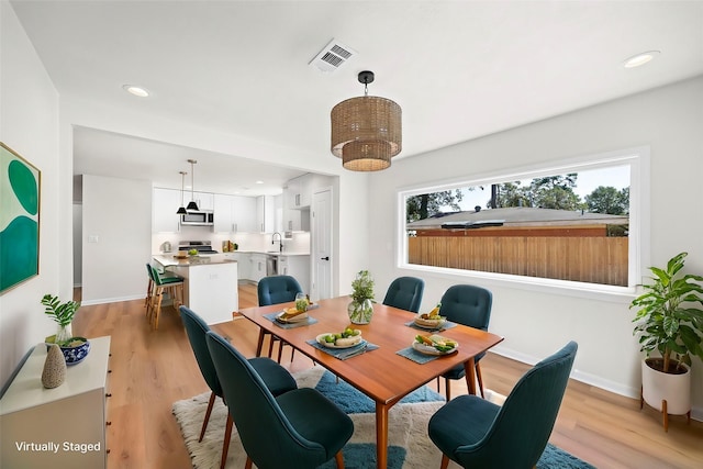 dining space with sink and light hardwood / wood-style floors