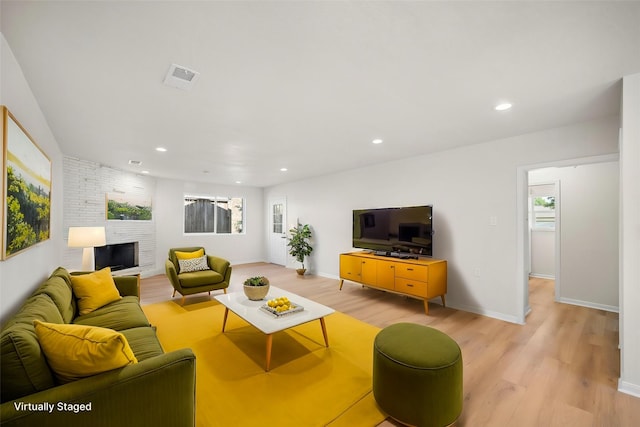 living room with a fireplace, light hardwood / wood-style flooring, and a healthy amount of sunlight