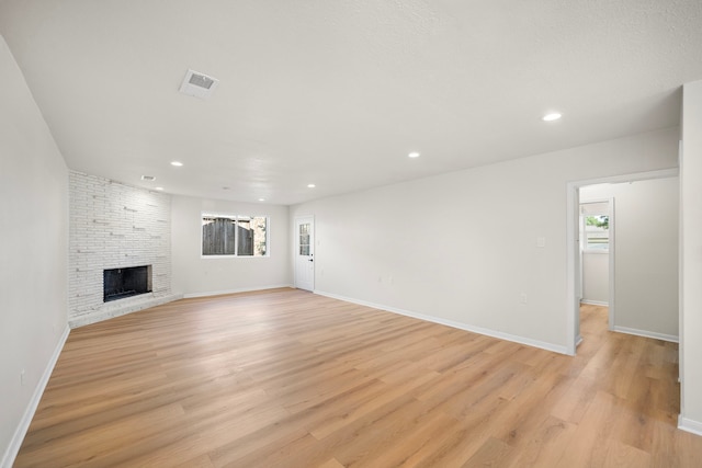 unfurnished living room with a fireplace, a healthy amount of sunlight, visible vents, and light wood finished floors