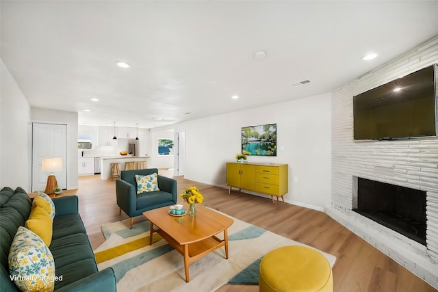 living room featuring light hardwood / wood-style flooring and a large fireplace