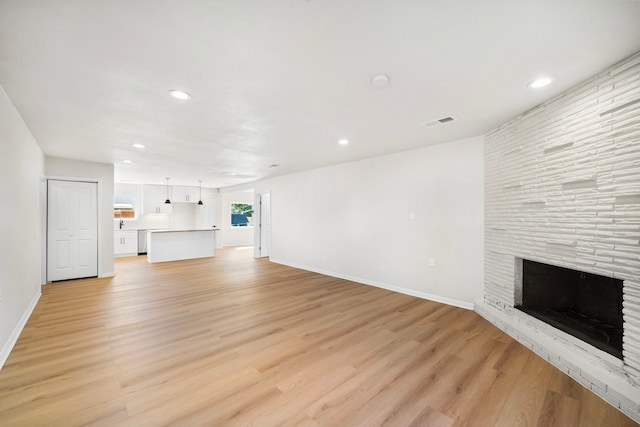 unfurnished living room featuring a fireplace and light hardwood / wood-style flooring