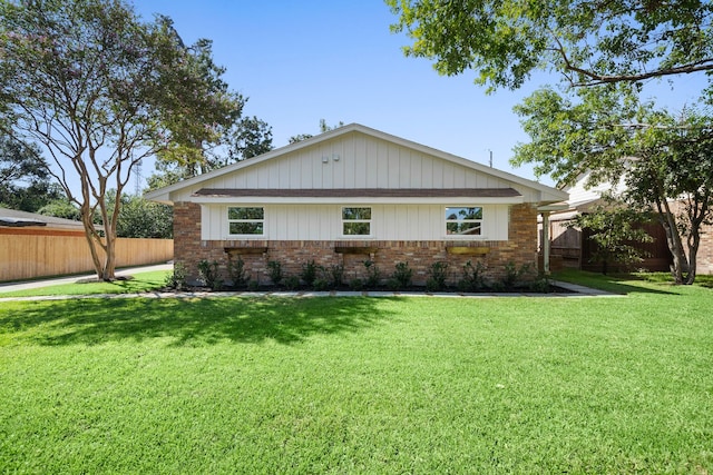 view of front of property featuring fence, brick siding, and a lawn