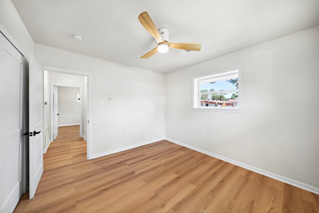 unfurnished bedroom with light wood-style flooring, baseboards, a closet, and ceiling fan