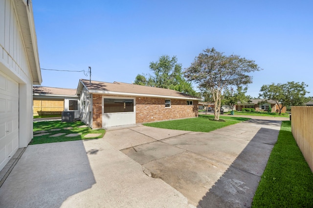 exterior space with fence, driveway, brick siding, a patio area, and a lawn