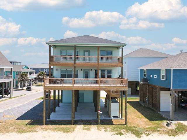 rear view of house featuring a balcony, driveway, a shingled roof, an attached garage, and a residential view