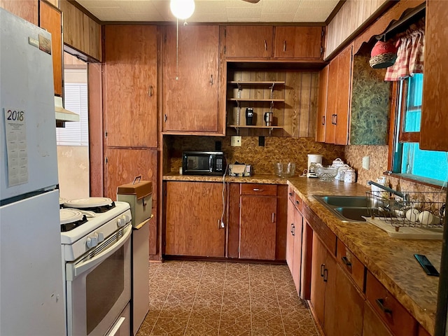 kitchen with a wealth of natural light, sink, decorative backsplash, white appliances, and wall chimney exhaust hood