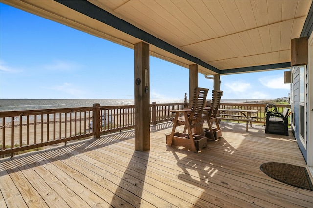 wooden deck featuring a water view and a beach view