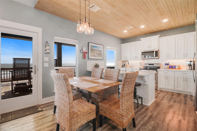 dining room with a healthy amount of sunlight, light hardwood / wood-style flooring, and wooden ceiling