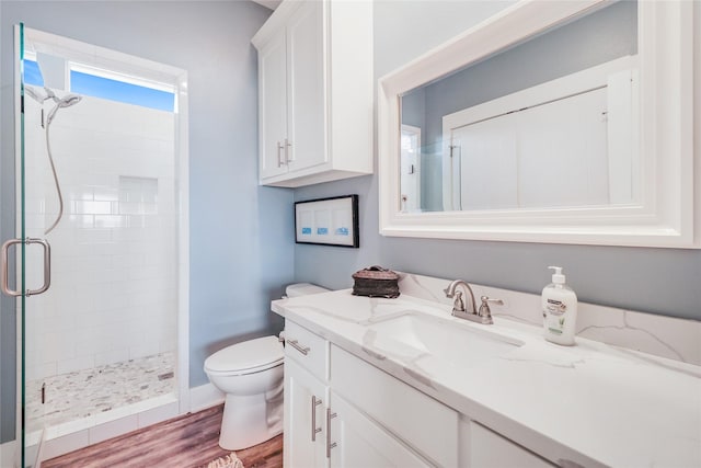 bathroom with wood-type flooring, toilet, an enclosed shower, and vanity