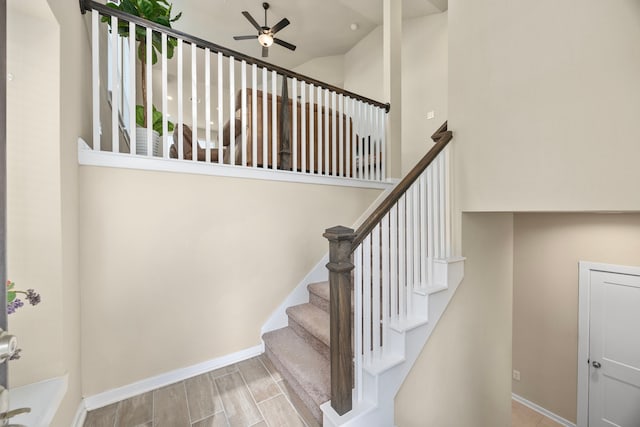 staircase featuring high vaulted ceiling and ceiling fan