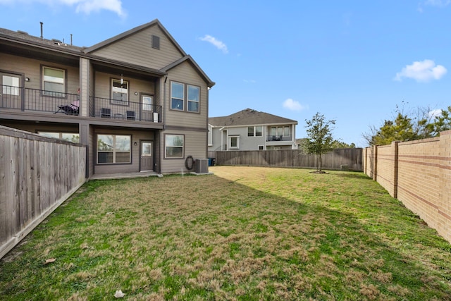 rear view of house featuring cooling unit, a lawn, and a balcony