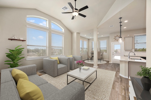 living room with lofted ceiling, sink, light hardwood / wood-style flooring, and plenty of natural light