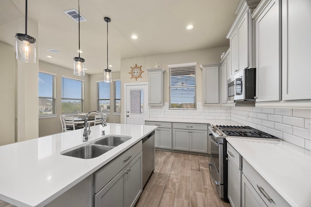 kitchen featuring gray cabinets, an island with sink, appliances with stainless steel finishes, and sink