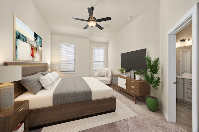 bedroom featuring ceiling fan, ensuite bath, sink, and light carpet