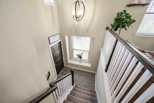 stairway featuring carpet floors, a towering ceiling, and a notable chandelier