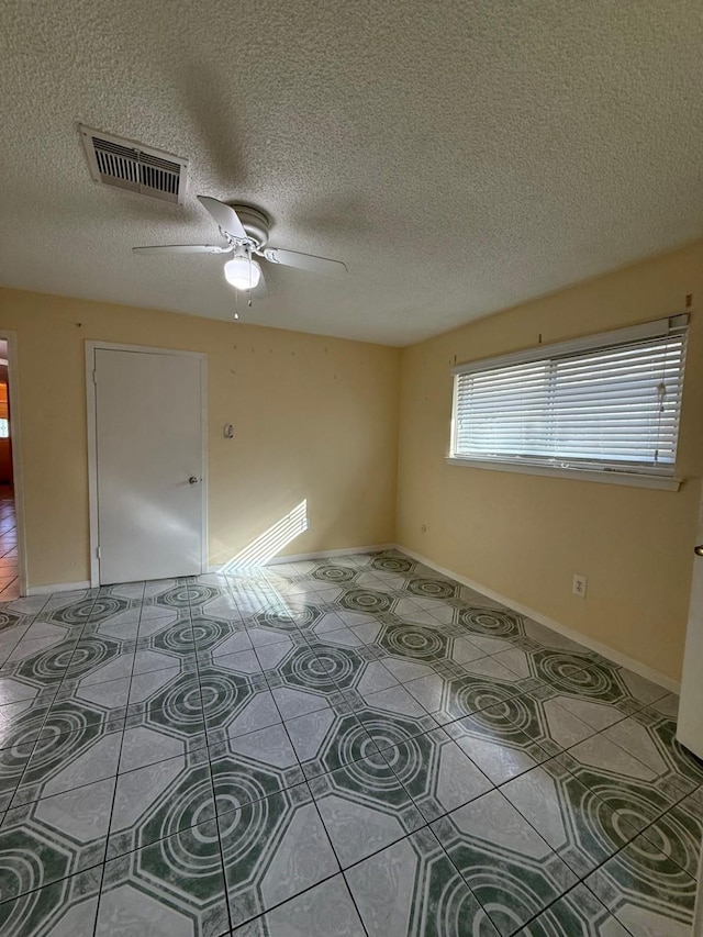 tiled spare room with ceiling fan and a textured ceiling