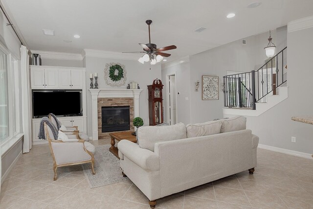 tiled living room featuring a fireplace, ornamental molding, and ceiling fan