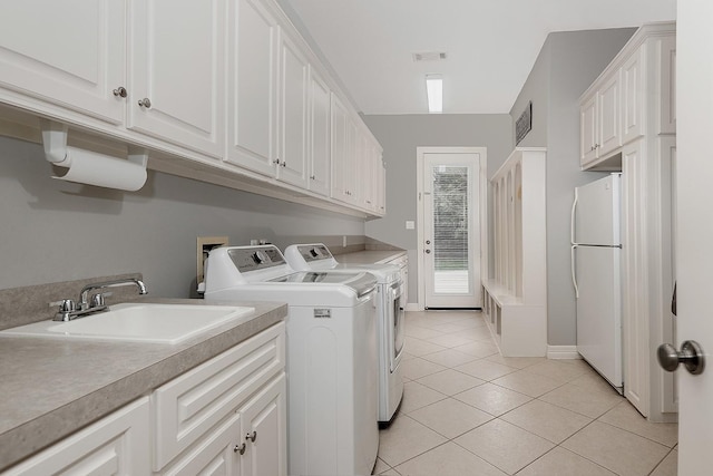 laundry room with cabinets, sink, washer and dryer, and light tile patterned floors