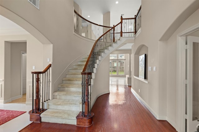 stairs with hardwood / wood-style flooring and a high ceiling