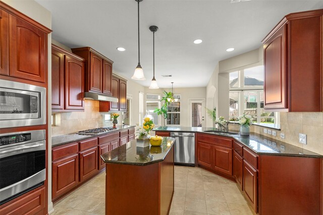 kitchen featuring sink, hanging light fixtures, stainless steel appliances, decorative backsplash, and kitchen peninsula