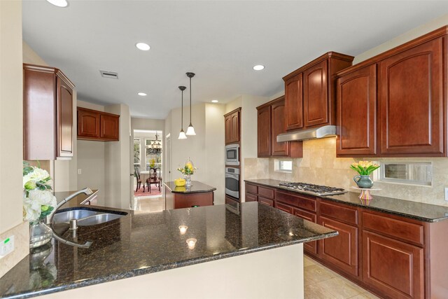 kitchen with appliances with stainless steel finishes, sink, dark stone countertops, and decorative light fixtures