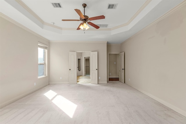 unfurnished bedroom with light carpet, a tray ceiling, and ornamental molding