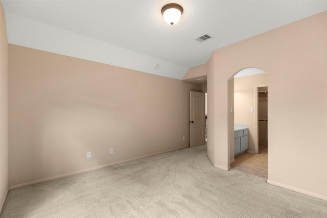 spare room with lofted ceiling and light colored carpet