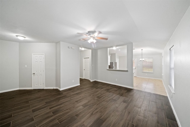 unfurnished living room featuring dark hardwood / wood-style flooring and ceiling fan with notable chandelier