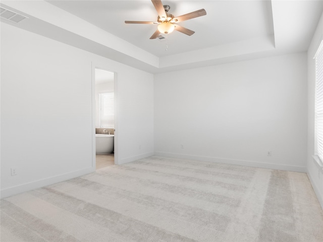 unfurnished room featuring ceiling fan, carpet flooring, a tray ceiling, and visible vents