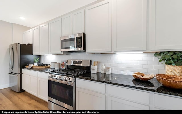 kitchen featuring dark stone countertops, appliances with stainless steel finishes, tasteful backsplash, and white cabinets