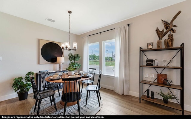 dining area featuring an inviting chandelier, hardwood / wood-style flooring, and vaulted ceiling