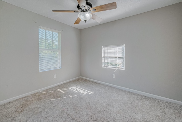 carpeted empty room featuring a wealth of natural light, a textured ceiling, and ceiling fan