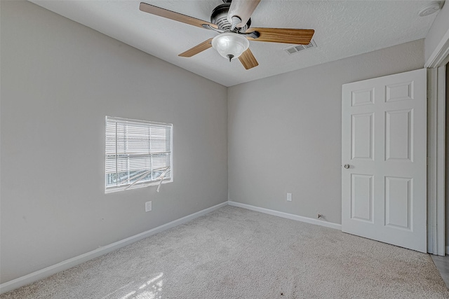 spare room featuring a textured ceiling, light colored carpet, and ceiling fan