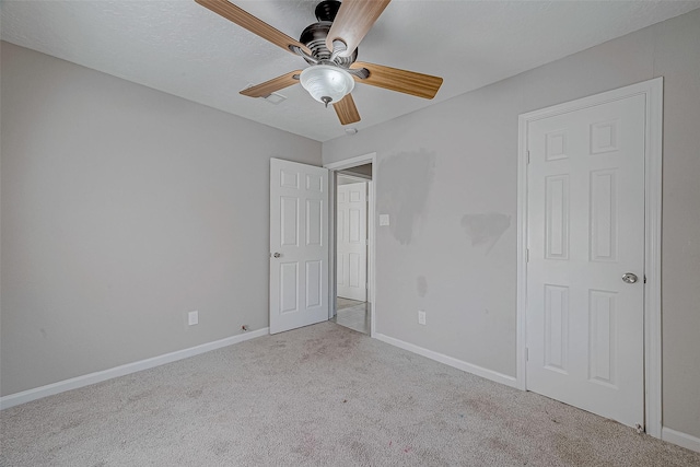 unfurnished bedroom with light carpet, a textured ceiling, and ceiling fan