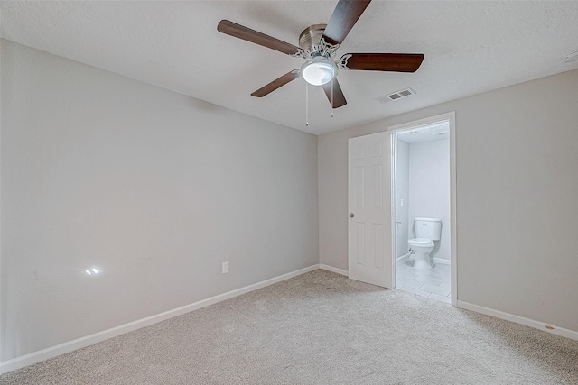 unfurnished bedroom with ceiling fan, ensuite bath, light colored carpet, and a textured ceiling