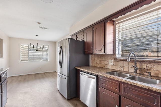 kitchen with sink, hanging light fixtures, plenty of natural light, stainless steel appliances, and decorative backsplash