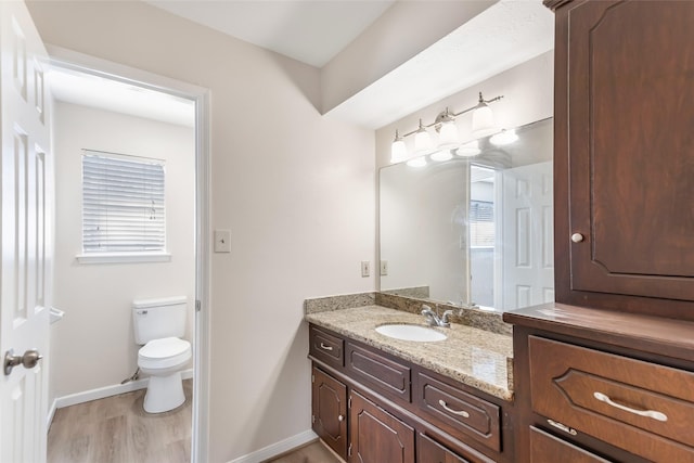 bathroom featuring hardwood / wood-style flooring, vanity, a healthy amount of sunlight, and toilet