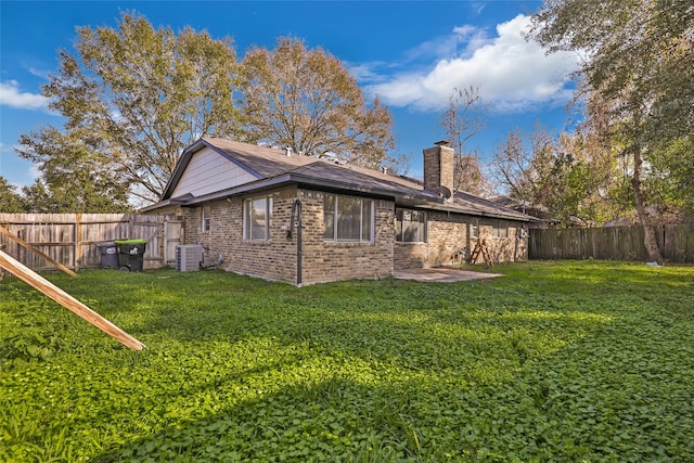 rear view of house with central AC, a patio area, and a lawn