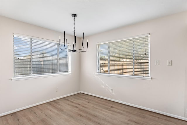 unfurnished dining area with a notable chandelier and hardwood / wood-style flooring