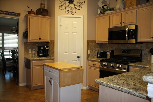 kitchen featuring light stone countertops, stainless steel appliances, a center island, and light brown cabinets