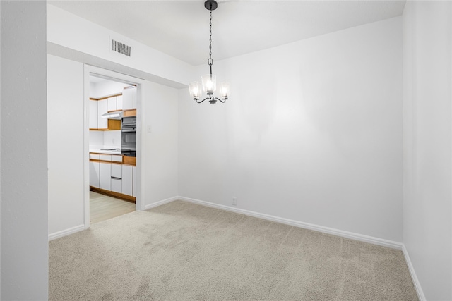 carpeted empty room with an inviting chandelier