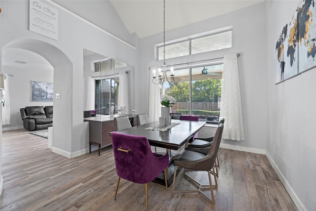 dining area with a notable chandelier, wood-type flooring, and high vaulted ceiling