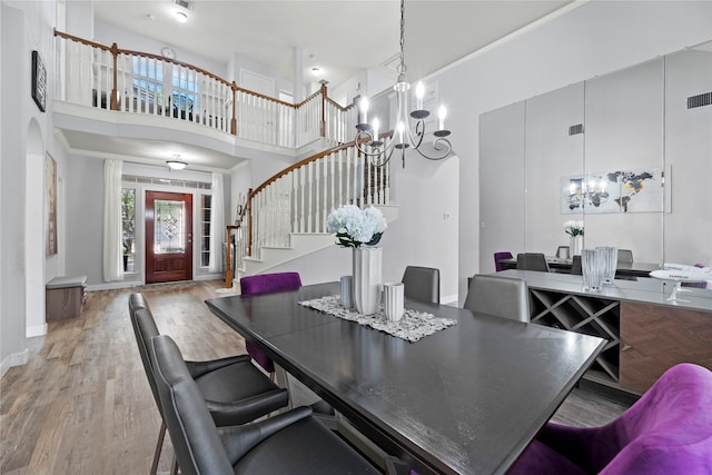 dining space with hardwood / wood-style flooring, a high ceiling, and a notable chandelier